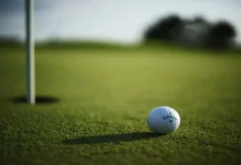 KANSAS CITY, UNITED STATES - Oct 11, 2021: A selective focus shot of a Callaway Golf ball near hole pin on a grass golf field.